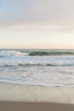 Yumuşak dalgalar huzur dolu bir alacakaranlıkta kumsalı okşar.