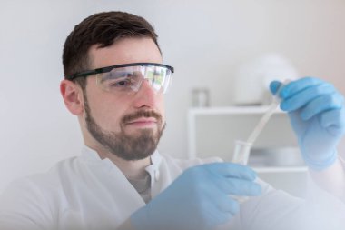 Laboratuvar gözlüklü bir bilim adamı laboratuarda çalışıyor.