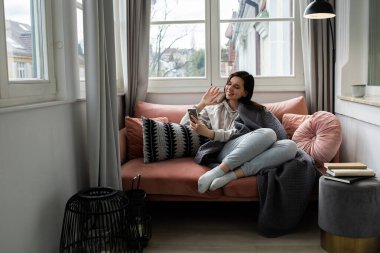 Antrenörde oturan genç bir kadın telefonda konuşuyor ve elini sallıyor.