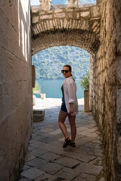 Kotor Körfezi 'ndeki eski taş duvarlardan geçen bir kadın.