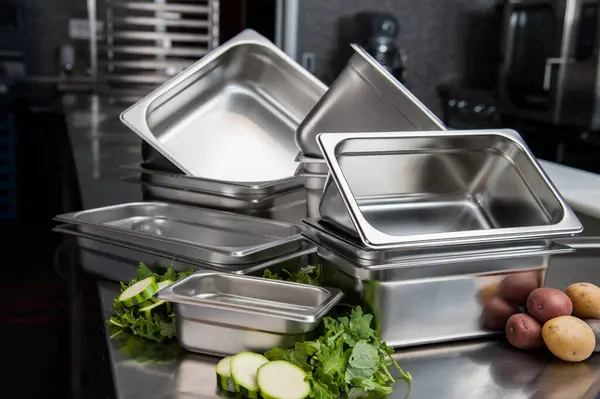 stock image Stacked stainless steel pans and fresh vegetables on prep table