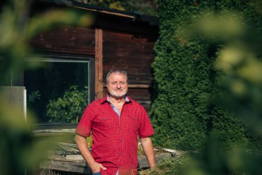 Kırmızı tişörtlü olgun bir adam Bahçede duruyor