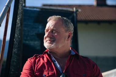 Kırmızı tişörtlü son sınıf öğrencisi Yansıtıcı bir gülümsemeyle yukarı bakıyor.