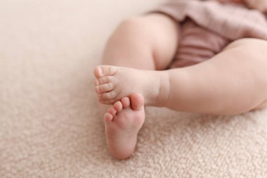 Açık pembe arka planda uzanmış bebek ayakları