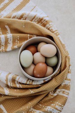 Kırsal kumaşa sarılı bir kasede çok renkli yumurtalar.