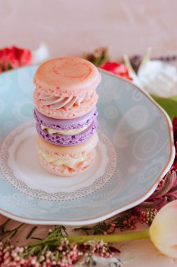 Stack of colorful macarons on a patterned plate clipart