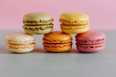 Vibrant macarons stacked against a pastel background clipart