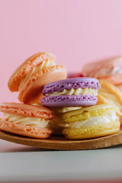 Stock image Stacked colorful macarons on a wooden plate with a pink backdrop