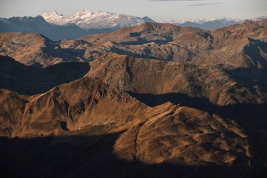 Dağlarda sonbahar sabahı, uzak karlı tepe, altın ışıklı ön plan