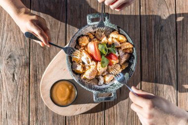 Güneşli bir tahta masada geleneksel bir Avusturyalı Kaiserschmarren 'i paylaşıyoruz.
