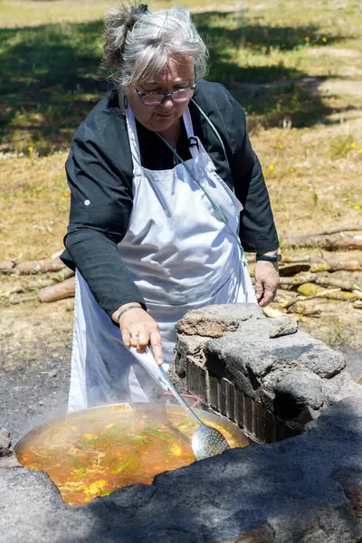 Beyaz önlüklü bir kadın tipik bir İspanyol paella pişiriyor.