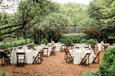 Bahçe resepsiyonu, masalar, sandalyeler ve ip ışıkları.