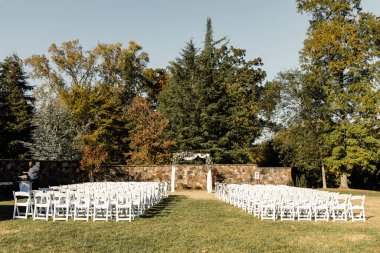 Beyaz sandalyeli ve çiçekli açık hava düğün töreni.
