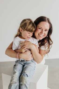 Gülümseyen anne, gülümseyen kızı kucaklıyor.