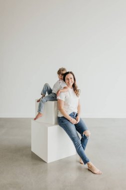 Anne ve kızı gülümserken ve birbirlerine yaslanırken otururlar.