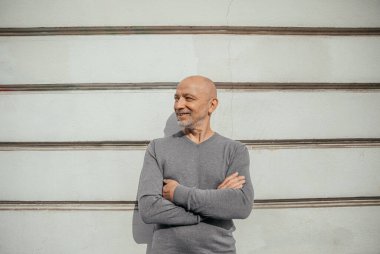 Kentin dokulu duvarına karşı duran kendinden emin kıdemli adam.