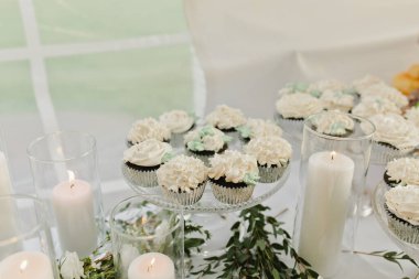 Yeşil ve uzun beyaz mumları olan zarif bir düğün masası.