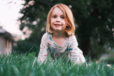 Güneşli bir günde dışarıda oynayan gülümseyen genç kız.