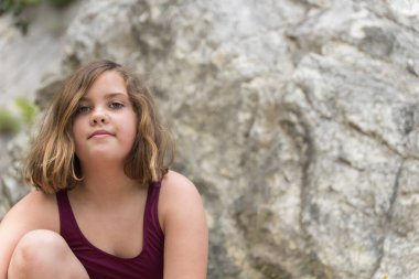 Bikinili güzel kız kayalıklarda oturuyor.