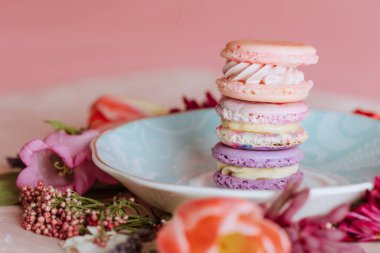 Çiçek desenli bir tabakta pastel kurabiyeler yığılmış.