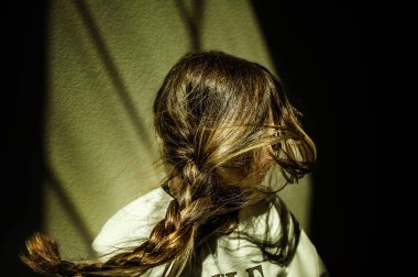 Uzun örgülü saçı olan genç bir kızın profili.