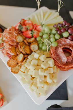 Şarküteri tahtasında taze et, peynir ve meyve var.