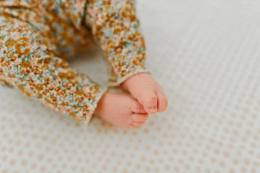 Newborn baby girl lays in crib with open toes clipart