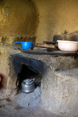 A blue pot sits on top of a stove in a dirt room clipart