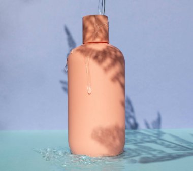 Pembe ürün şampuan şişesi arka planda suyla birlikte