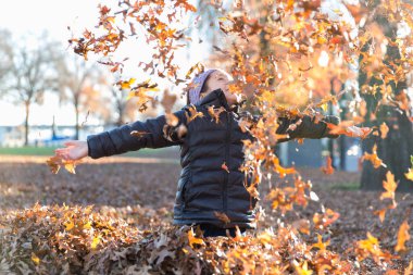 Neşeli kız Portland 'da sonbahar yapraklarıyla oynuyor.