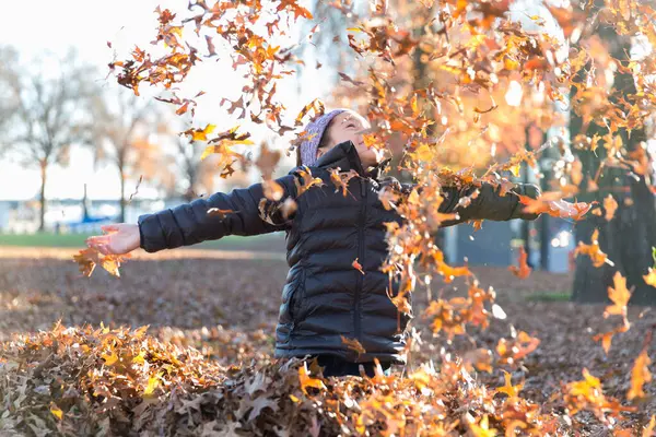 Neşeli kız Portland 'da sonbahar yapraklarıyla oynuyor.