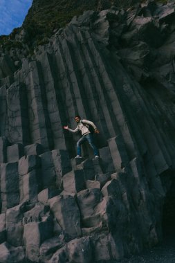 Reynisdrangar plajında Reynisfjara sütunlarında bir adam var..