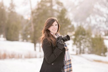 Happy women holding camera in snow in lake tahoe clipart