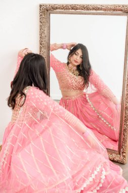 Pembe sari giyen kadınlar aynaya bakar.