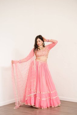 Ayakta duran ve pembe elbisesinden şal tutan kadınlar.