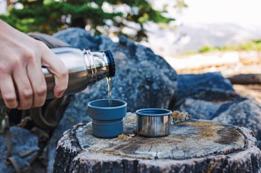 Erkek elinin termo mataradan sıcak çay doldurduğu yakın plan.