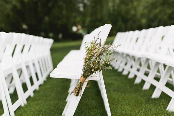 White Folding Chairs Set up with wildflower aisle decor and eucalyptus