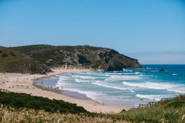 Portekiz 'in batı Algarve sahilinde dalga tepeleri ve insanları var.