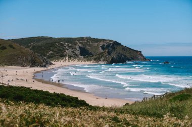 Portekiz 'in batı Algarve sahilinde dalga tepeleri ve insanları var.