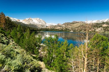Parlak yansıması ve berrak gökyüzü ile görkemli dağ gölü