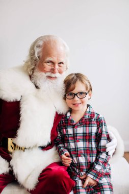 Noel Baba ve ekose pijamalı bir çocuk. Kapalı mekan dekorasyonu.