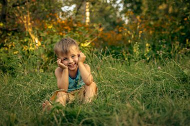 Köydeki çimlerin üzerinde neşeli bir çocuk