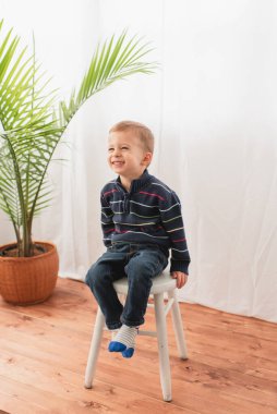 Neşeli çocuk stüdyo ortamında oturup gülümsüyor.