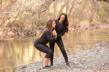 Kadın eğitmen bayana nasıl çömelmesi gerektiğini gösteriyor.