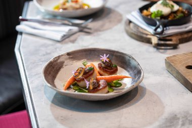 Havuç ve istiridye tabağı yan masada otururken görülüyor.