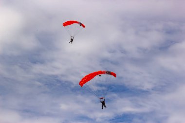 İki paraşütçü bulutlu bir gökyüzünden iniyor..