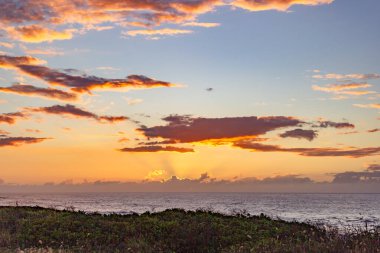 Vibrant sunset with dramatic clouds over the ocean in Hawaii. clipart