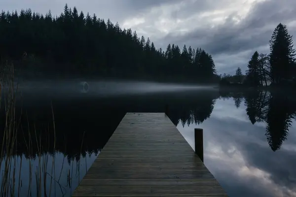 stock image Small dock on reflective Scottish loch with fog