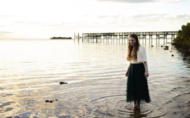 Kıvırcık saçlı genç bir kadın Pi 'nin yanında sığ suda yürüyor.