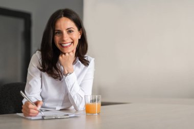 Portrait of young business woman smilling and writting clipart